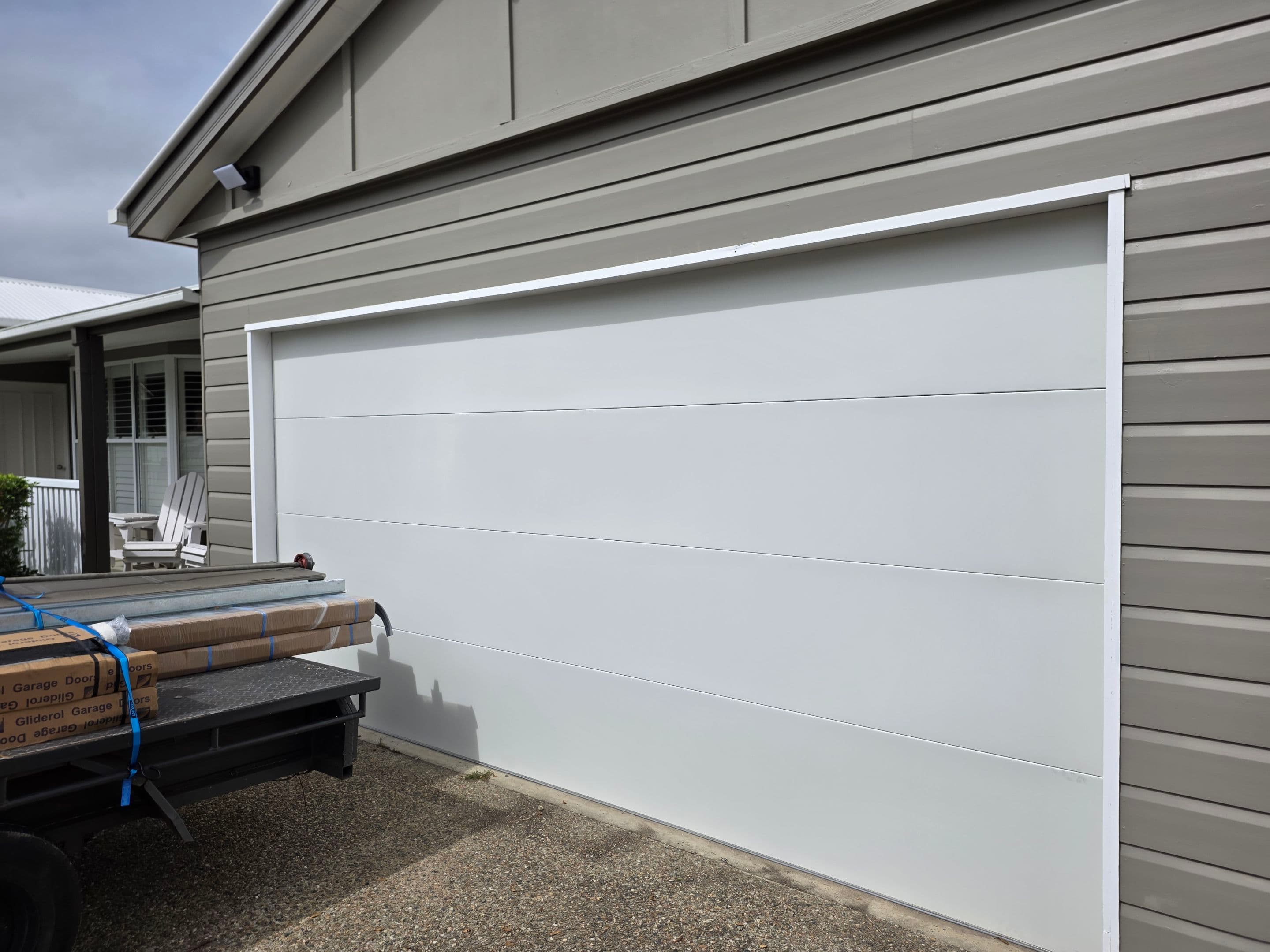 Deadlock Garage Doors job underway at a Sunshine Coast home, door sections on the trailer